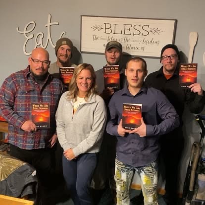 A group of residents holding books and smiling together during a study group inside His House of Hope